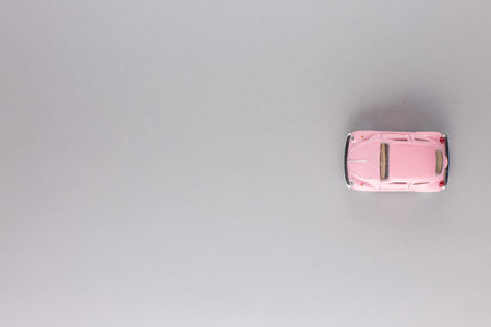 A pink car figurine, shot from above, white background.