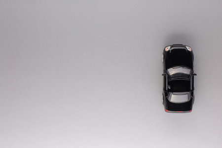 Top view of a new black car figurine, aligned to the right, on gray background.の写真素材