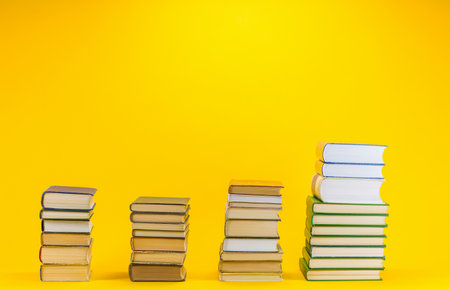 Columns of different sizes made from books on yellow background.の写真素材