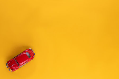 A red car figurine shot from above, on yellow background, aligned at the bottom left.の写真素材