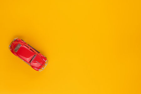 A red car figurine shot from above, on yellow background, aligned to the left.の写真素材