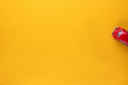A red car figurine shot from above, on yellow background, aligned to the right.の写真素材