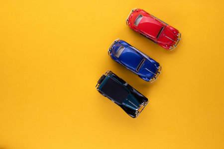 Three different colored car figurines on yellow background, shot from above.の写真素材