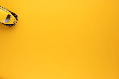 An yellow car figurine shot from above, on yellow background, aligned at the top left.の写真素材