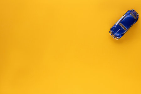 A blue car figurine shot from above, on yellow background, aligned at the top right.の写真素材