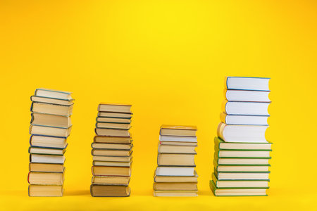 Columns of different sizes made from books on yellow background.の写真素材