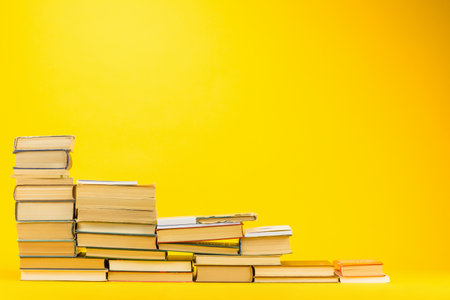 A descending staircase made from books on yellow background.の写真素材
