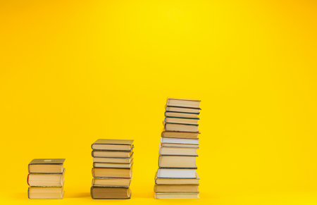 Columns of different sizes made from books on yellow background.の写真素材