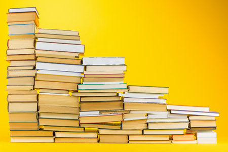A descending staircase made from books on yellow background.の写真素材