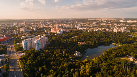 Shot of a highway road located in the middle of a green forest next to a small lake, leading towards a big city, during a majestic sunrise.の写真素材