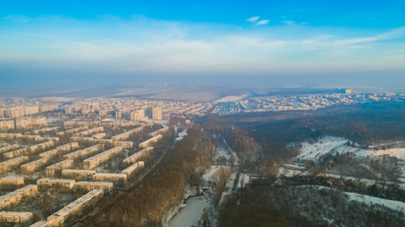 Aerial view of a beautiful city and a small forest and a frozen lake, during a cold, snowy winter.の写真素材