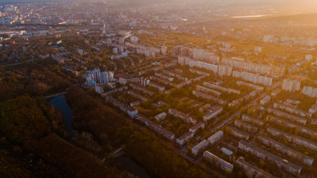 Aerial view of a beautiful city located at the edge of a forest, of a cloudy blue sky, and a small lake, during sunrise.の写真素材