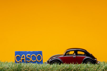 Chisinau, Moldova - August 15th 2019: A crimson car figurine aligned to the left on grass next to a blue sign with the words test drive on it, on orange background.のeditorial素材