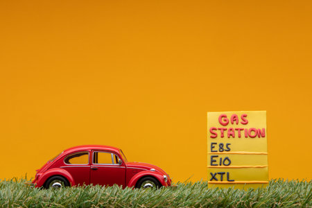 Chisinau, Moldova - August 15th 2019: A red car figurine aligned to the left on grass next to an yellow gas station sign.のeditorial素材
