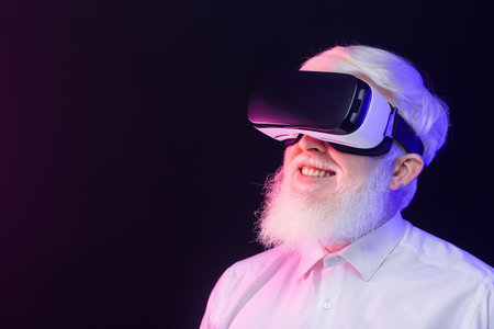 Closeup view of an old albino man wearing a vr set and looking to the left, isolated on a beautiful, colorful background.の写真素材