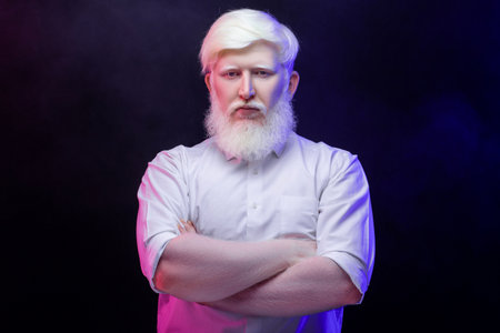 An old albino grandfather looking thoughtfully towards the camera, isolated on a beautiful, colorful background.の写真素材