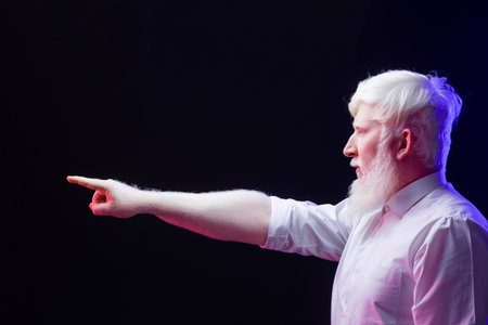 An old albino grandfather pointing towards the left, isolated on a beautiful, colorful background.の写真素材