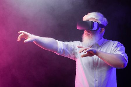 Portrait of an old albino grandfather trying to reach something while wearing vr isolated on a beautiful, colorful background.の写真素材