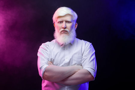 An old albino grandfather looking thoughtfully towards the camera, isolated on a beautiful, colorful background.の写真素材