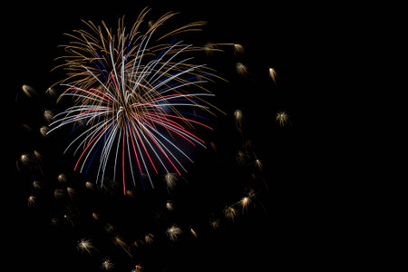 Red, white and blue firework exploding with smaller fireworks surrounding the large explosionの写真素材