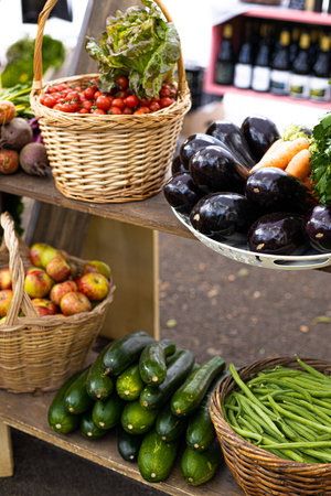 Organically produced fruits and vegetables arranged on shelves at a local market stall. Everything is arranged in wicker baskets.fruits and vegetables are fresh, shiny and properly displayedの写真素材