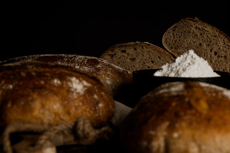 horizontal photo of artisan breads cut from wholemeal flour with jar of flour on rustic wooden table...