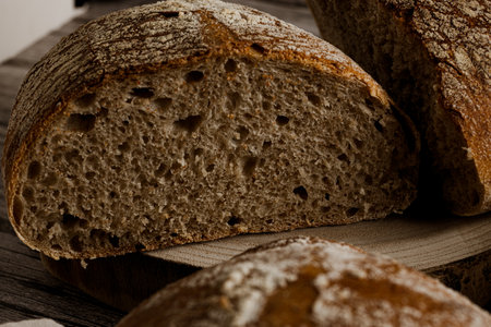 close-up photo of several artisan breads cut from wholemeal flour with a jar of flour on a rustic...