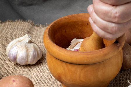 a cook performs kitchen work, with garlic, onions, potatoes, mortar and other rustic kitchen...