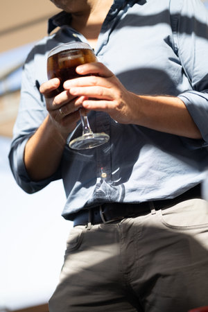 Man holding a glass of cola in the street, close-upの写真素材