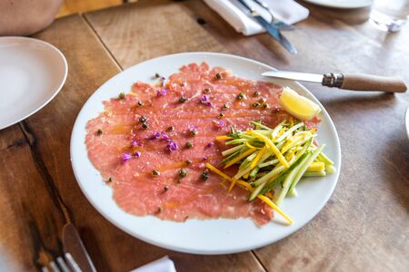 Beef carpaccio, beef tenderloin, zucchini, capers on the tableの写真素材