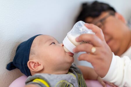 Father holding and feeding his baby. Child is 4 months old