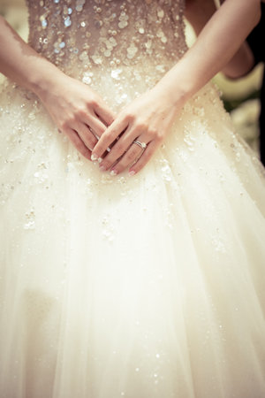 Beautiful wedding dress with lace and sequins in the hands of the brideの写真素材