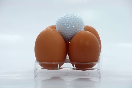 Golf ball and egg on a white backgroundの写真素材