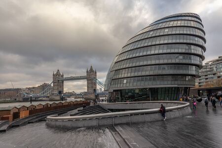 London, England - november 2019. Riverside view at modern building of London City Hall  and famous Tower Bridge. Autumn, grey clouds over classic cityscapeのeditorial素材