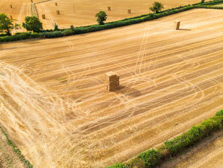 Aerial view of Hay bales stacked in agricultural field post-harvest. High quality photo over farmland.の写真素材
