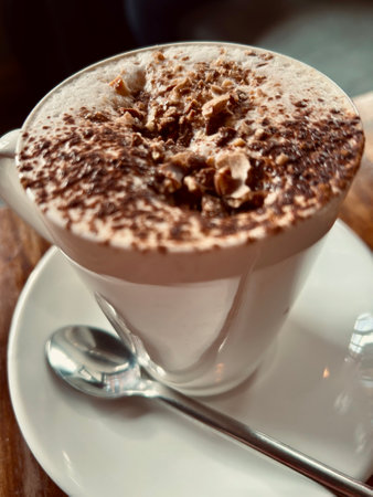 Luxury coffee latte with chocolate hazelnut dusting. Luxurious hot drink with white saucer in a cafe.の写真素材