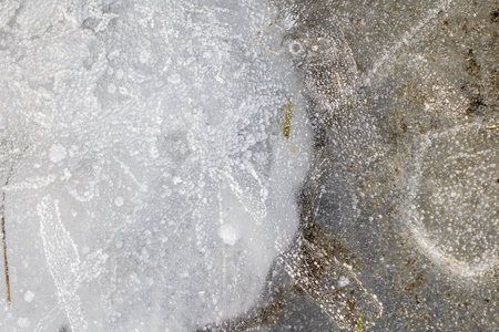 Frozen icy lake water with air bubbles and frost during winter at Skelton Lake, West Yorkshire