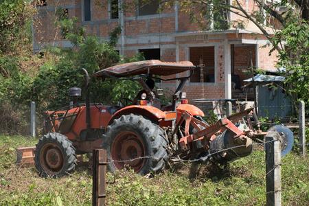 The orange plow is working in the fields on a sunny day.