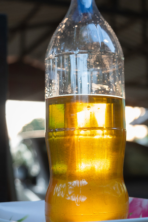 Hand is pouring the used oil into a clear bottle.の写真素材