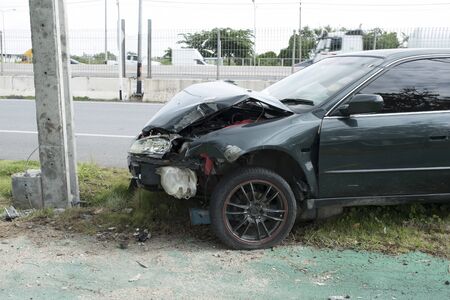 Green cars drive with negligence quickly. And collided with the electric pole until it was damaged,Car accident and waiting to be done from insurance to take care of the damage.の写真素材