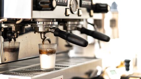 Close-up of espresso top white milk pouring from automatic coffee machine. Professional coffee...