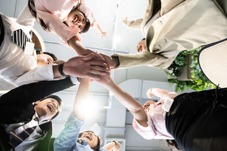 Young team putting hands up for new startup in creative office,Cheerful people giving strength motivation,focus on hand,Co-working and teamwork concept,working the job successの写真素材