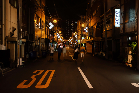 Osaka, Japan - August 05, 2014 : Late Night Street view, people are walking in the middle of the road towards the incoming car.のeditorial素材