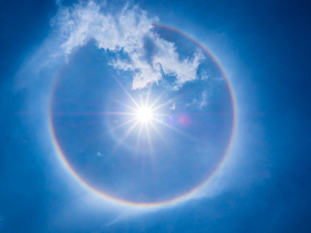The clear circular rainbow surround the bright sun, its phenomenon of the sun halo. The phenomenon is occurred by the light and moisture refraction.の写真素材