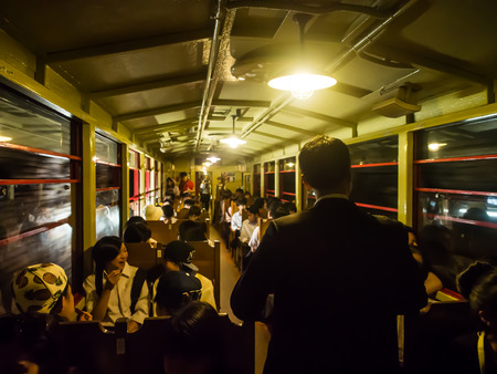 Kyoto, Japan - Jun 4, 2016 : The enjoyable moment of people inside a moving train through a tunnel. A girl is happily talking to her friend, a man is standing in a walkway, and another boy is eating.のeditorial素材