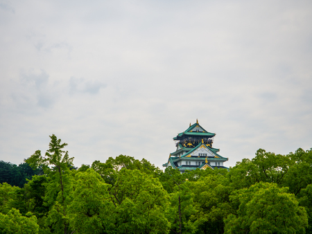 Selective focus on the great main landmark's building of Osaka in the middle of the green jungle trees, Osaka castle. The castle is high above all of forest and its decorated construction is charming.のeditorial素材