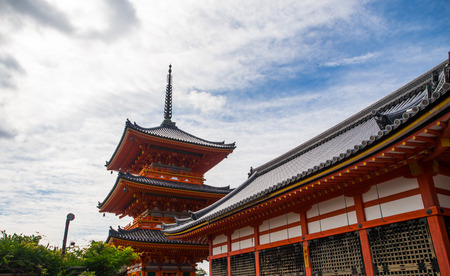 The nice clear sky of the day with the red japanese shrine tower and the pattern of the japanese buddhism temple' structure in Kiyomizu in Kyoto, Japan.の写真素材
