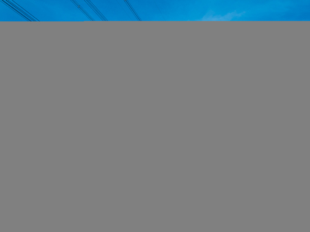 The beautiful landscape of yellow paddy in agriculture field with the dangerous electric transmission tower or high voltage poles in the middle. The blue sky is very bright and clear.の写真素材