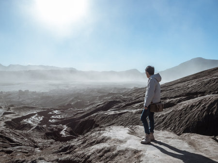 A guy with the view of dried lava terrain from active volcano in Bromo Tengger Semeru National Park,...