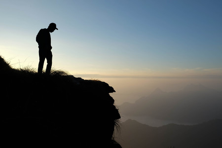 Silhouette man looking down from mountain